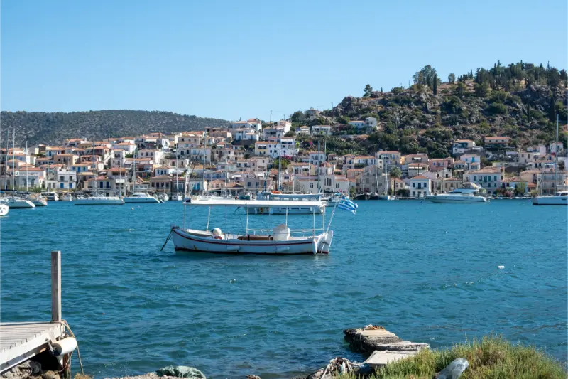 Poros Island Greece Traditional Fishing Boat Anchored Blue Sea Coastal Town Hillside Houses